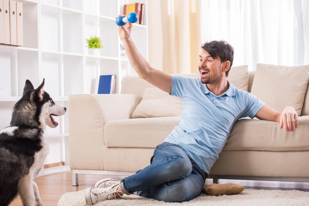 man playing with dog inside