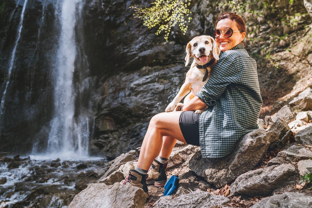 woman hugging dog near waterfall